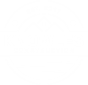 Knowles Construction Logo – Established 2017 Knowles Construction logo with a blue and white color scheme. The logo features the text "Knowles Construction" in bold blue letters beneath an image of three rooflines, symbolizing houses, with the establishment year "Est. 2017" above. The design is encircled with a semi-circular border and a wave pattern below the text.
